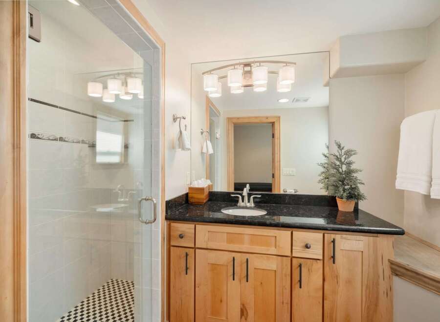 This modern bathroom features a spacious glass-enclosed shower with elegant tilework and a striking black and white checkered floor.