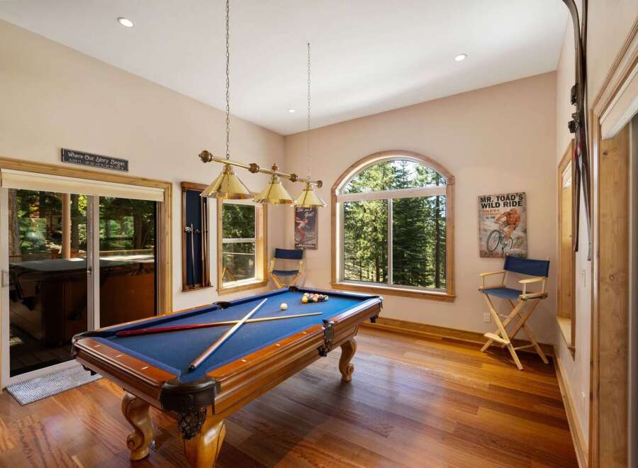 Enjoy endless entertainment in this game room featuring a full-size pool table and a scenic view of the surrounding forest.