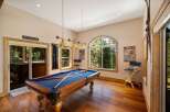 Enjoy endless entertainment in this game room featuring a full-size pool table and a scenic view of the surrounding forest.