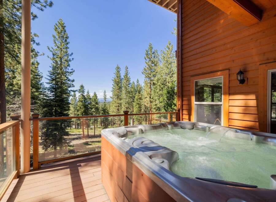 Experience ultimate relaxation in this stunning mountain retreat, featuring a luxurious hot tub on a spacious deck overlooking a serene forest landscape.