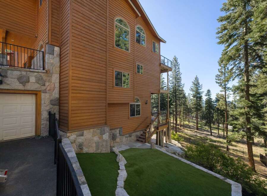 Experience luxury mountain living in this stunning wood-sided home, featuring a stone-accented exterior and a spacious garage.