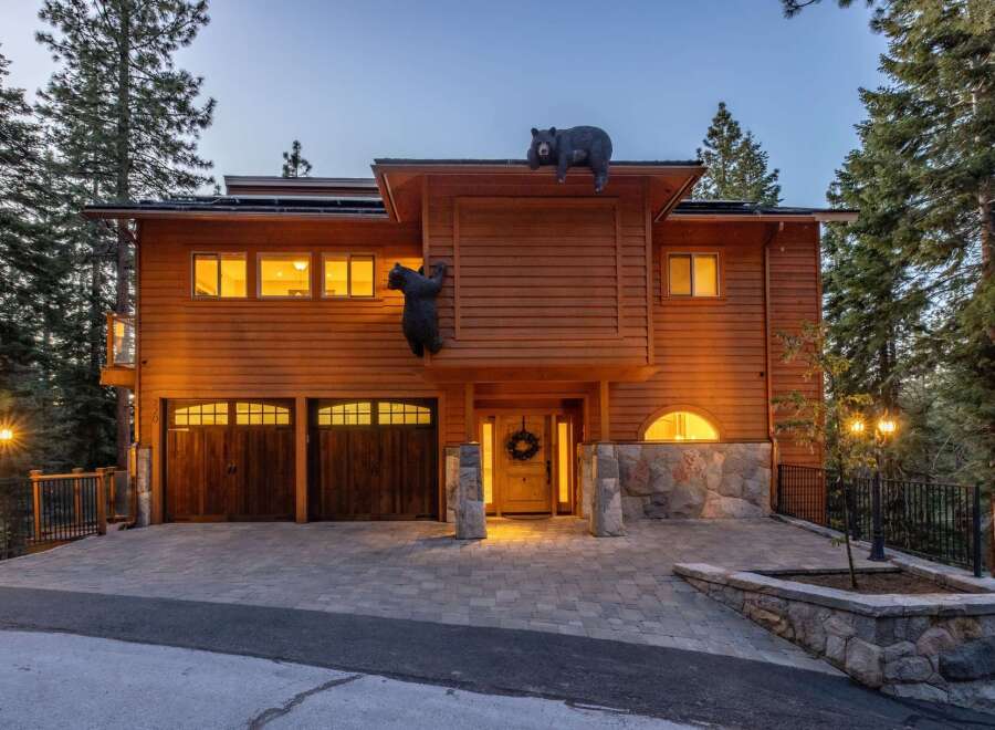 Experience rustic charm with this stunning wooden home, featuring playful bear sculptures adorning the roof and exterior.