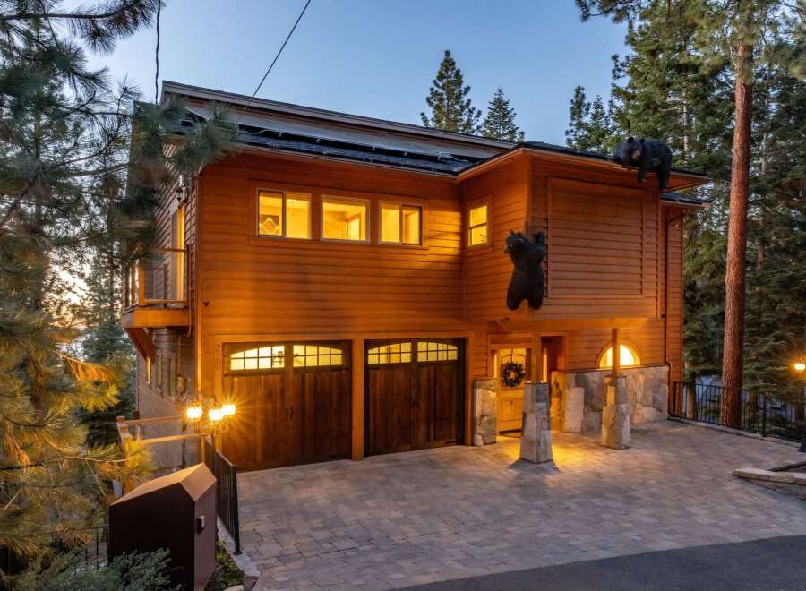 Experience luxury mountain living in this stunning wooden home, featuring a unique bear-themed exterior and a spacious paver driveway leading to a double garage.