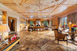 Experience unparalleled luxury in this stunning wood-paneled living room, featuring an intricate coffered ceiling with a compass rose inlay and a grand fireplace.