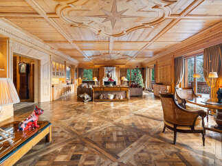 Experience unparalleled luxury in this stunning wood-paneled living room, featuring an intricate coffered ceiling with a compass rose inlay and a grand fireplace.