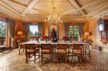 Experience rustic elegance in this stunning dining room, featuring a grand wooden table set for a feast under a magnificent chandelier.