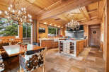 Experience rustic luxury in this charming wooden kitchen, featuring a large dining table with unique cowhide chairs and ornate chandeliers.