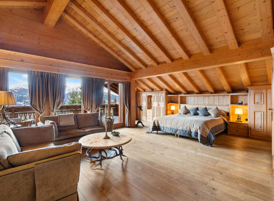 Experience luxurious mountain living in this stunning chalet bedroom, featuring a spacious king-size bed with plush bedding and a cozy seating area.