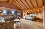 Experience luxurious mountain living in this stunning chalet bedroom, featuring a spacious king-size bed with plush bedding and a cozy seating area.