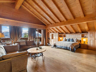 Experience luxurious mountain living in this stunning chalet bedroom, featuring a spacious king-size bed with plush bedding and a cozy seating area.
