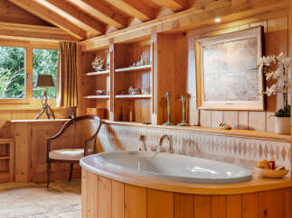 Experience ultimate relaxation in this luxurious wooden bathroom, featuring a deep soaking tub with stunning forest views.
