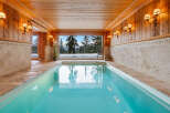 Experience ultimate relaxation in this indoor swimming pool, featuring a stunning panoramic view of a snowy mountain landscape.
