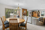 Enjoy mountain views from this spacious dining and living area, featuring a large wooden dining table with chairs and a cozy living room with a fireplace and entertainment center.