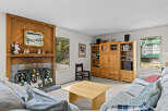 Cozy living room featuring a warm wood-paneled fireplace with festive holiday decor and a large wooden entertainment center.
