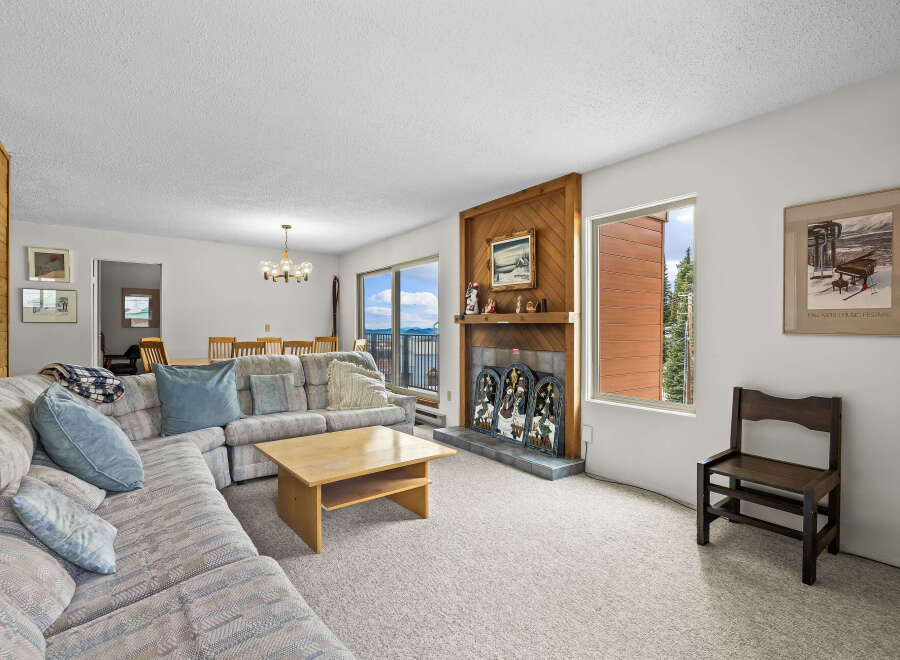 Experience breathtaking mountain and water views from this spacious living area, featuring a cozy fireplace and ample seating.