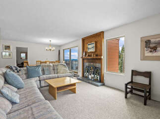Experience breathtaking mountain and water views from this spacious living area, featuring a cozy fireplace and ample seating.