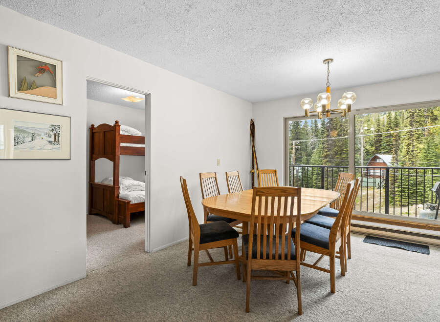 This dining area features a large wooden table with six chairs, perfect for family meals.