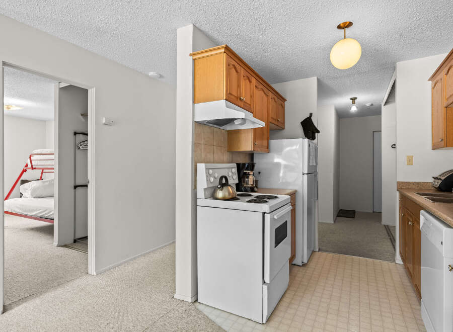 Discover this charming kitchen featuring warm wooden cabinetry and a functional white stove.