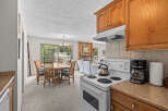 Experience comfortable living in this inviting space, featuring a well-appointed kitchen with a stove and coffee maker, adjacent to a dining area with a round wooden table and chairs.