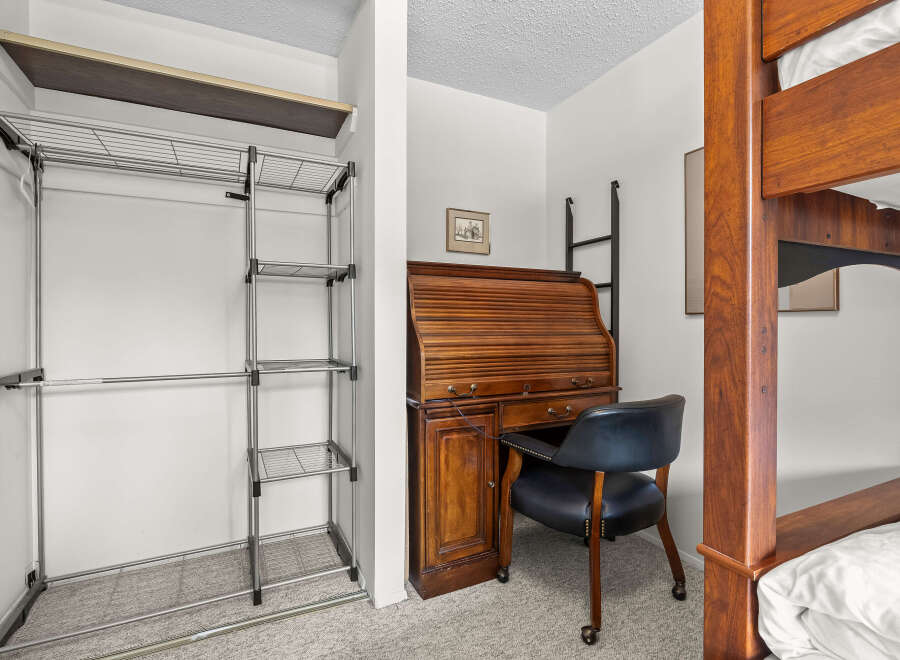 This bedroom offers a space-saving solution with a built-in closet system and a compact desk area, perfect for students or small living spaces.