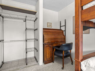 This bedroom offers a space-saving solution with a built-in closet system and a compact desk area, perfect for students or small living spaces.