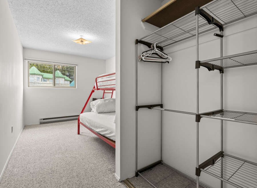 This charming bedroom features a space-saving red bunk bed, perfect for families or guests.