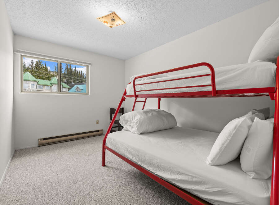 This charming bedroom features a vibrant red bunk bed, perfect for families or guests.