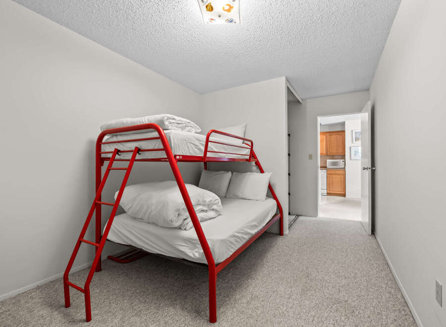 This charming bedroom features a vibrant red bunk bed, perfect for accommodating guests or children.