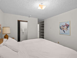 Step into this inviting bedroom featuring a comfortable bed dressed in crisp white linens, perfect for a restful night's sleep.