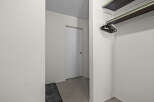 Discover ample storage solutions in this property, featuring a convenient closet with a built-in shelf and a rack of black hangers.