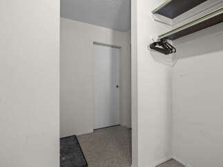Discover ample storage solutions in this property, featuring a convenient closet with a built-in shelf and a rack of black hangers.