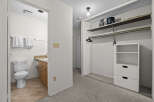 Discover a well-appointed bathroom featuring a toilet and vanity, complemented by a spacious closet with shelving and hanging space.