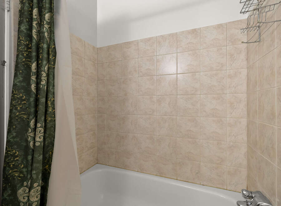 This bathroom features a classic tiled shower surround in a neutral beige tone, offering a clean and timeless aesthetic.