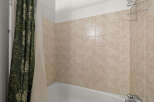 This bathroom features a classic tiled shower surround in a neutral beige tone, offering a clean and timeless aesthetic.