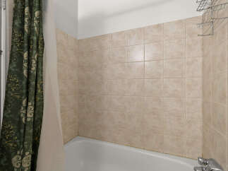 This bathroom features a classic tiled shower surround in a neutral beige tone, offering a clean and timeless aesthetic.