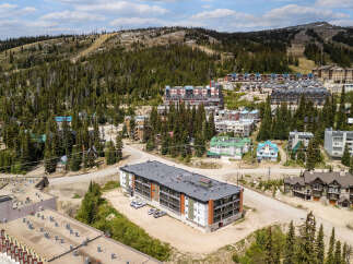 Discover this stunning mountain resort property, featuring modern multi-story buildings nestled amidst a lush pine forest.