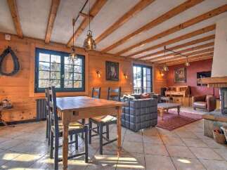 Experience rustic charm in this spacious living and dining area, featuring exposed wooden beams and a cozy fireplace.