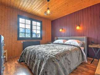 Experience cozy mountain living in this charming bedroom featuring warm wood paneling and a plush, inviting bed.