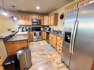 Discover this charming kitchen featuring beautiful natural wood cabinetry and granite countertops.