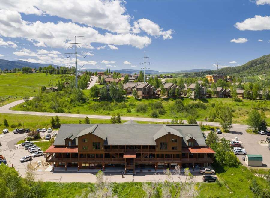 Discover this stunning multi-story wooden lodge nestled amidst rolling green hills and picturesque mountain scenery.