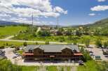 Discover this stunning multi-story wooden lodge nestled amidst rolling green hills and picturesque mountain scenery.