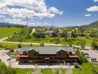 Discover this stunning multi-story wooden lodge nestled amidst rolling green hills and picturesque mountain scenery.