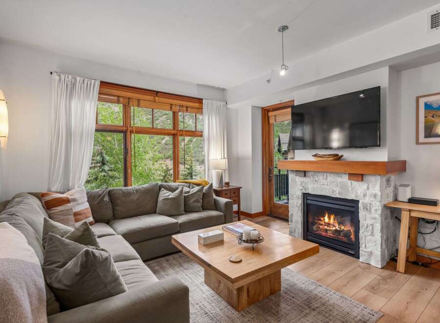Cozy up by the fireplace in this inviting living room, featuring a plush sectional sofa perfect for relaxing.