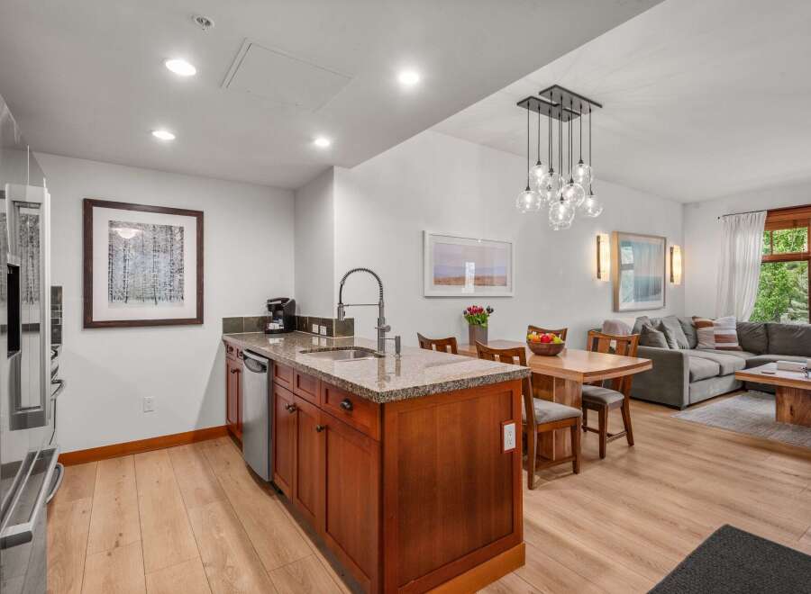 Experience modern living in this open-concept space featuring a sleek kitchen island with granite countertops and a stylish faucet.