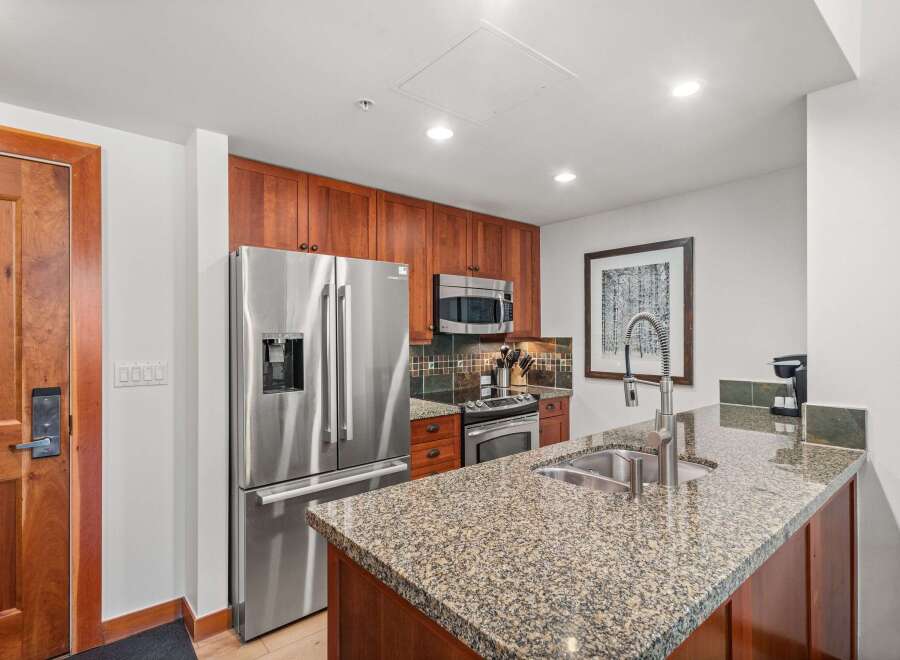 Experience modern living in this beautifully appointed kitchen, featuring sleek stainless steel appliances, granite countertops, and rich cherry wood cabinetry.