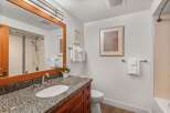 This bathroom features a granite-topped vanity with a wooden cabinet, a modern sink, and a brushed nickel faucet.