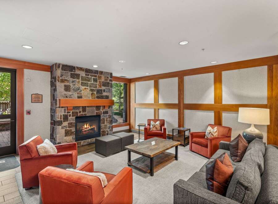 Cozy up by the stone fireplace in this inviting living area, featuring comfortable seating and a rustic coffee table.
