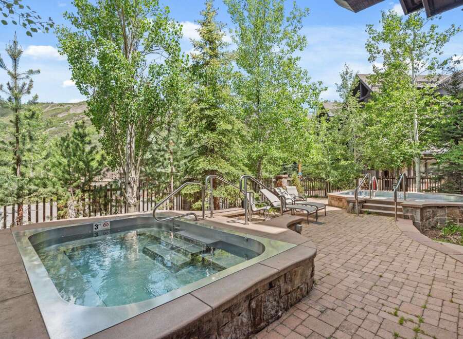 Enjoy a relaxing soak in this luxurious outdoor hot tub, surrounded by lush greenery and mountain views.