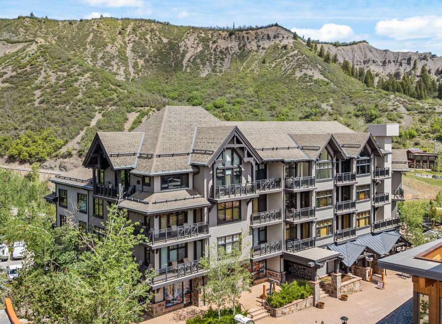 Experience luxury mountain living in this stunning condominium complex, nestled against a dramatic hillside backdrop.