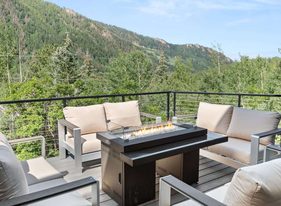 Experience breathtaking mountain views from this stunning deck, complete with a modern fire pit and comfortable seating.